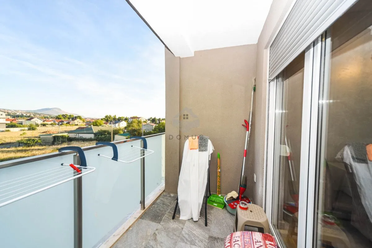 Covered balcony with a clothes drying rack and cleaning supplies.