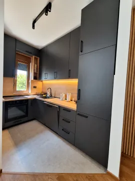 Moderna kuhinja tamnih elemenata sa drvenim detaljima i ugradnim uređajima. - image 5