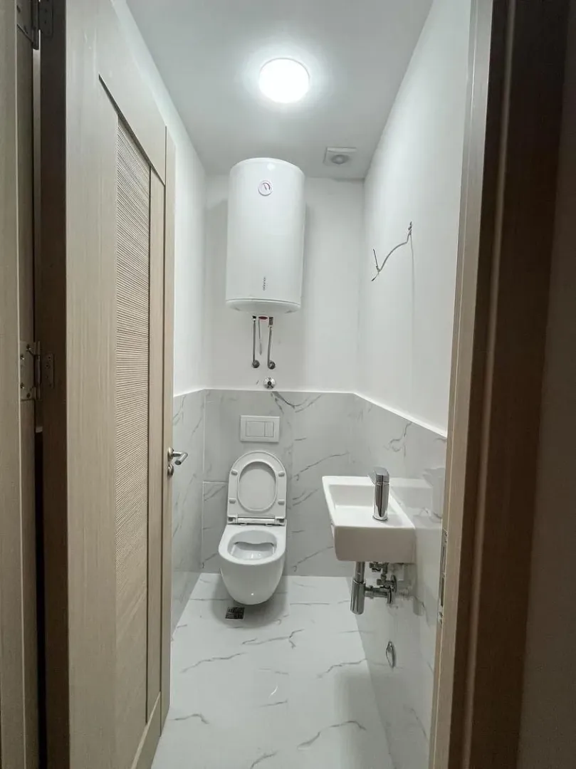 Manje kupatilo sa WC šoljom, umivaonikom i bojlerom.
