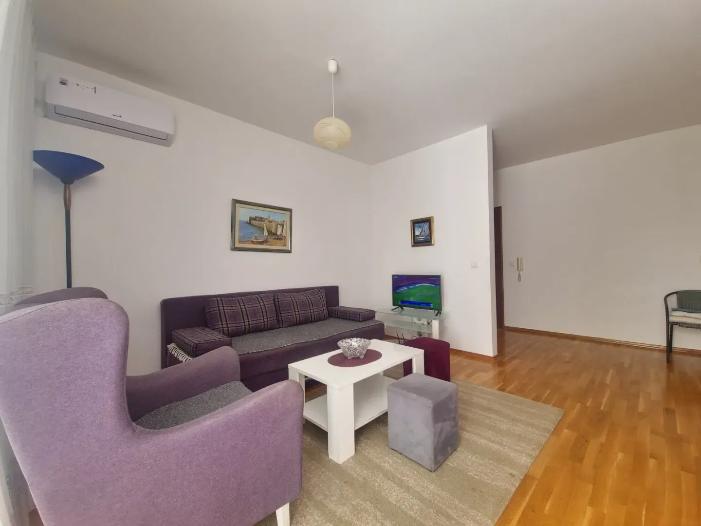 Dnevna soba sa garniturom, stočićem i televizorom.