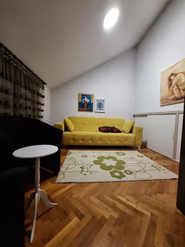 Living room with a yellow sofa and hardwood flooring. - image 13