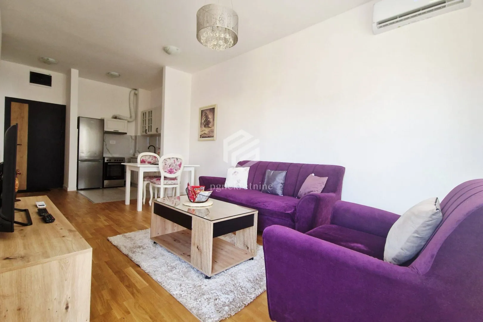 Living room with a purple sofa set and a dining area in the background.