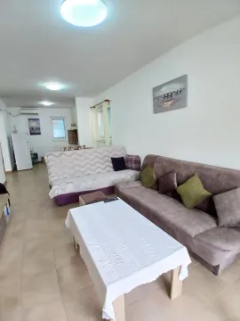 Dnevni boravak sa garniturom za sedenje, stočićem i pogledom na kuhinjski deo u pozadini. - image 8