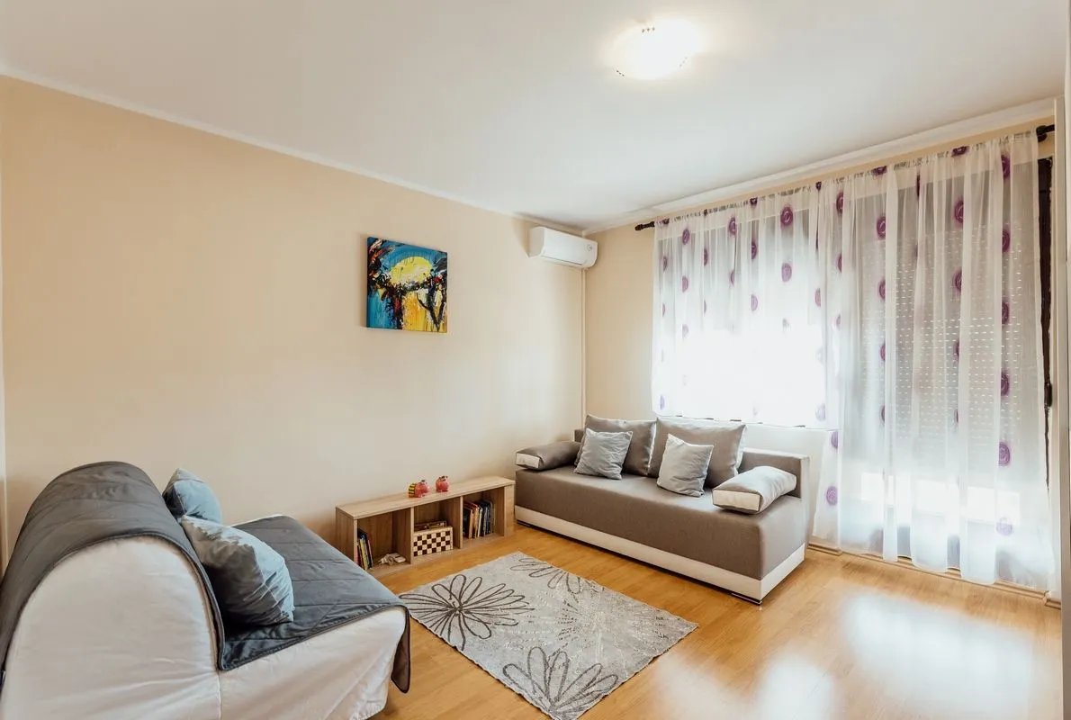 Living room with a sofa seating set and a window with white curtains.