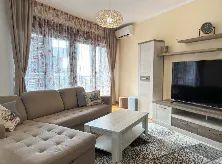 Dnevna soba sa garniturom, televizorom i trpezarijskim dijelom.