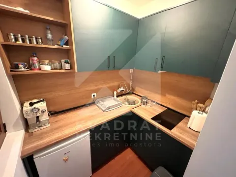 Manja kuhinja sa drvenim radnim površinama, plavim elementima i osnovnim kućnim aparatima. - image 3