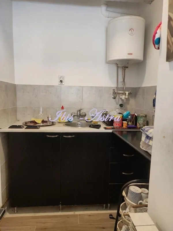 Small kitchen with a sink, dark cabinets, and a water heater on the wall.