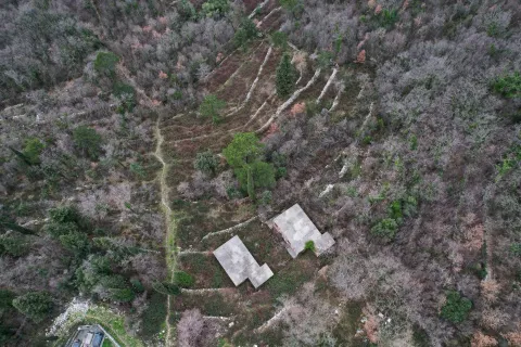Pogled iz vazduha na plac sa objektima okruženim šumom. - image 12