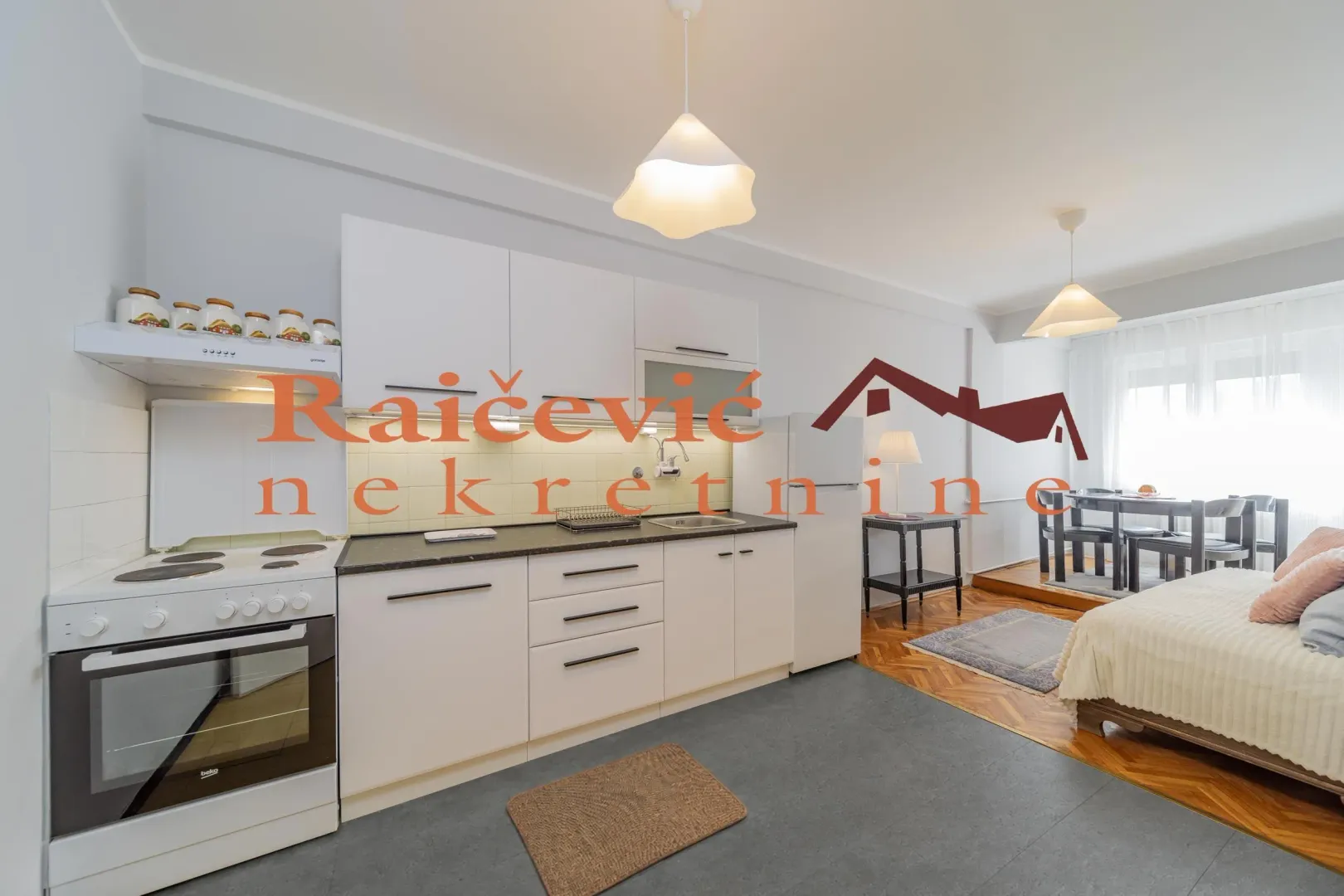 View of the kitchen with white cabinetry and an electric stove in an open-plan space.