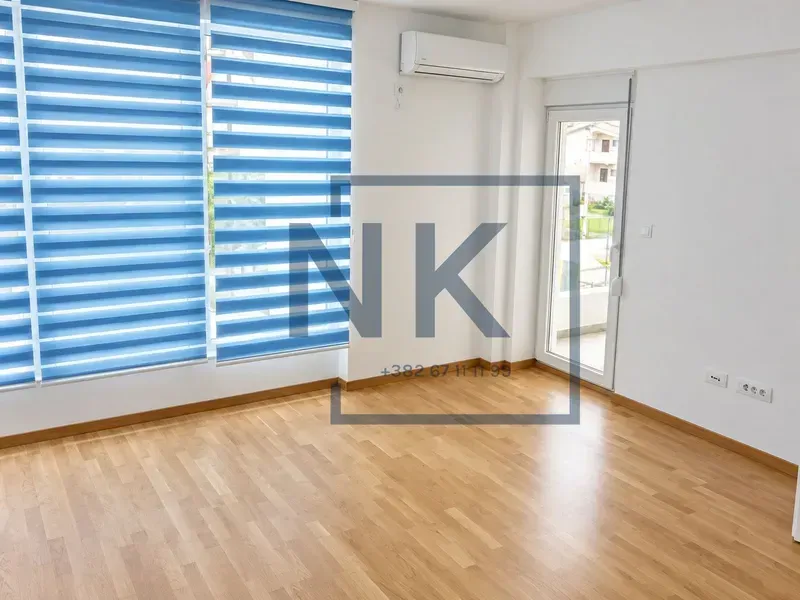 Prazna svijetla prostorija sa parketom, velikim prozorima i klima uređajem.