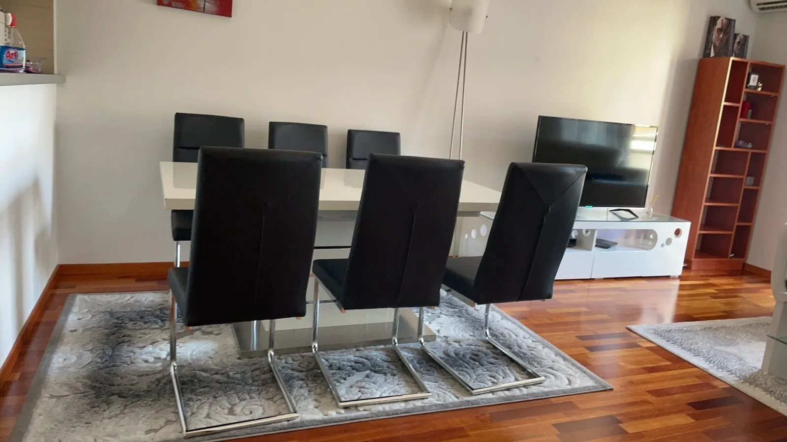 Svijetao trpezarijski prostor sa modernim stolom i crnim stolicama.