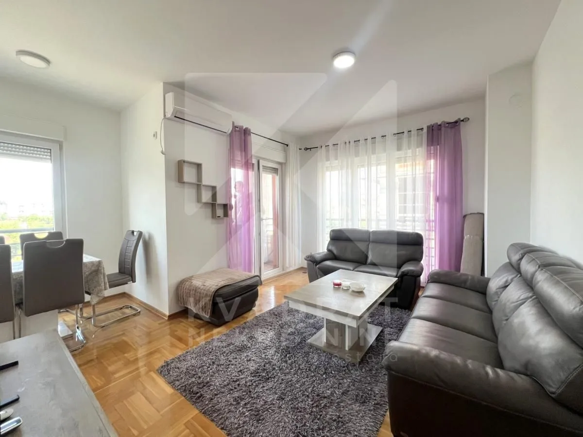 Spacious living room with a sofa set, coffee table, and dining area in the background.