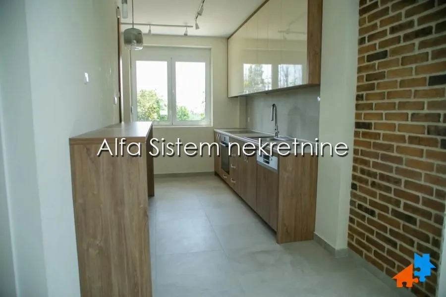 Long kitchen with wooden elements and a brick wall.