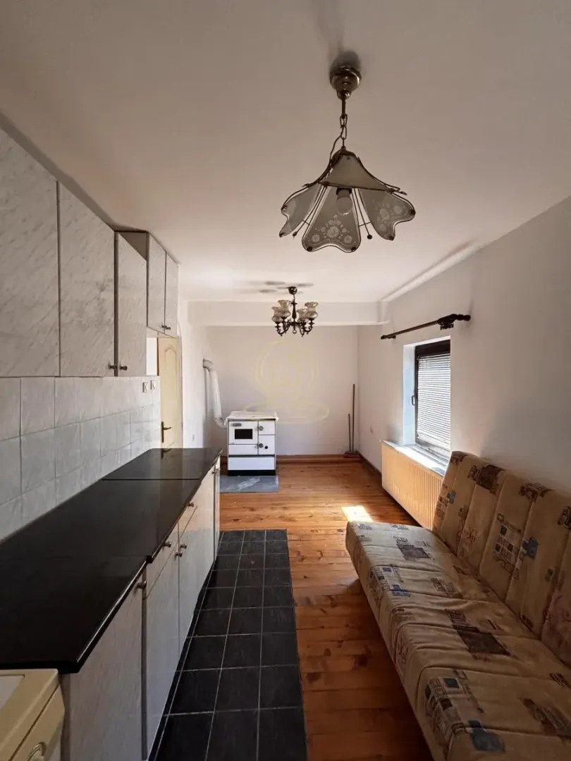 Long kitchen with cabinets and a sofa.