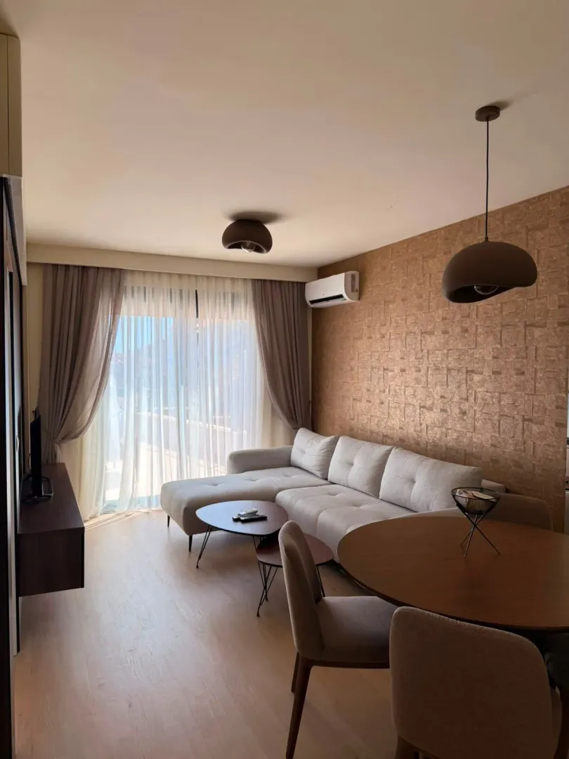 Living room with sofa, dining table and balcony access.