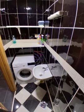 Kupatilo sa crnim pločicama, umivaonikom i mašinom za veš. - image 15