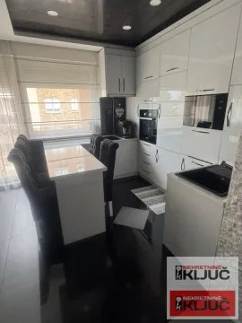 Moderna bela kuhinja sa ugrađenim aparatima i trpezarijskim stolom sa stolicama. - image 7