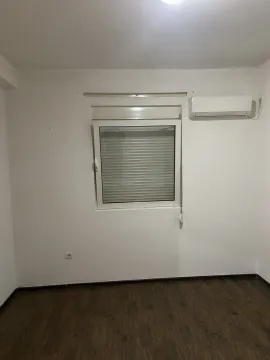 Prazna soba sa bijelim zidovima, prozorom i klima uređajem. - image 4