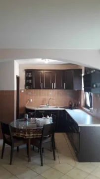 Kuhinja sa tamnim elementima i trpezarijskim stolom. - image 6