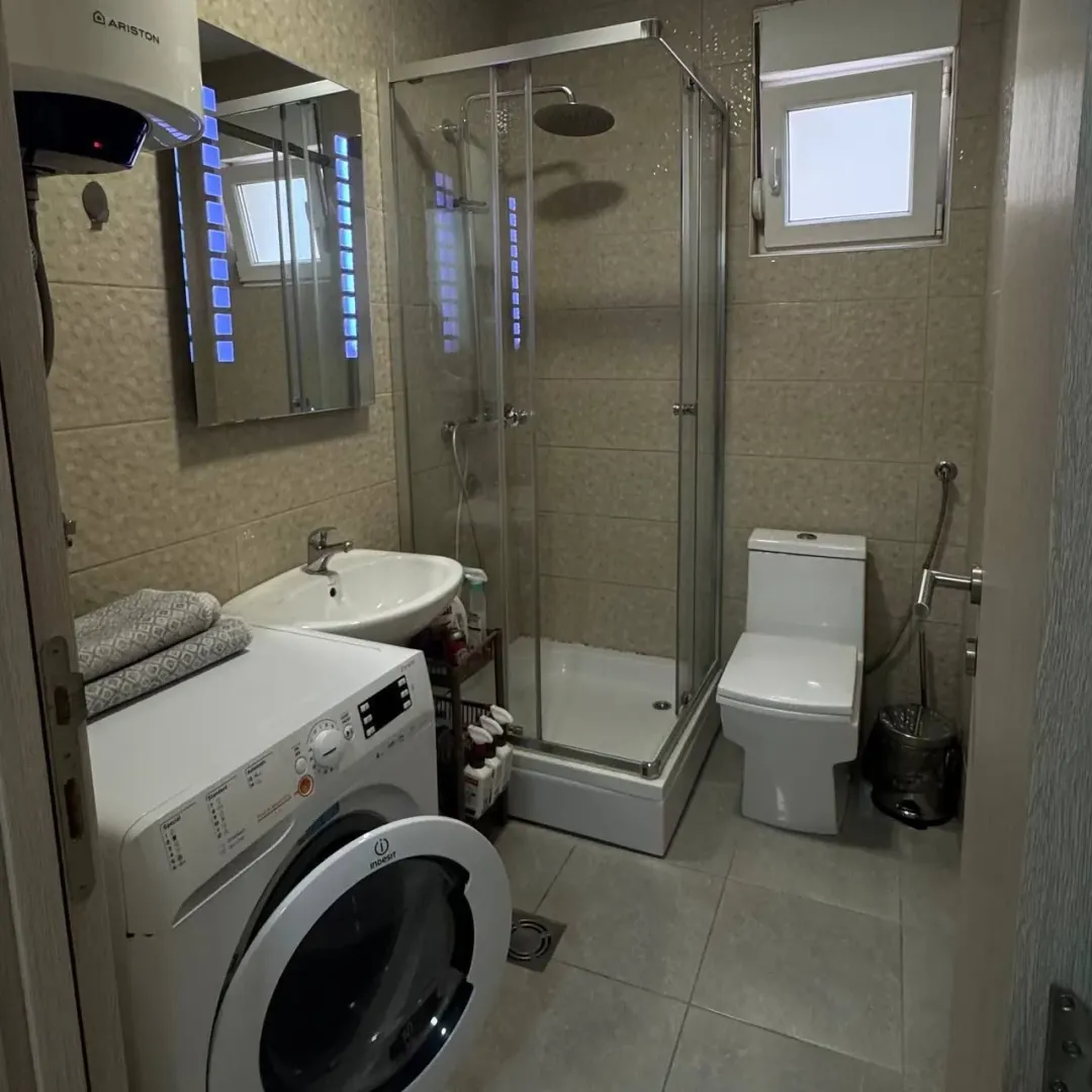 Small bathroom with a shower cabin, sink, and washing machine.