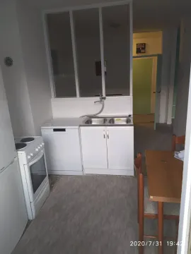 A simple kitchen with white appliances and a dining table. - image 5