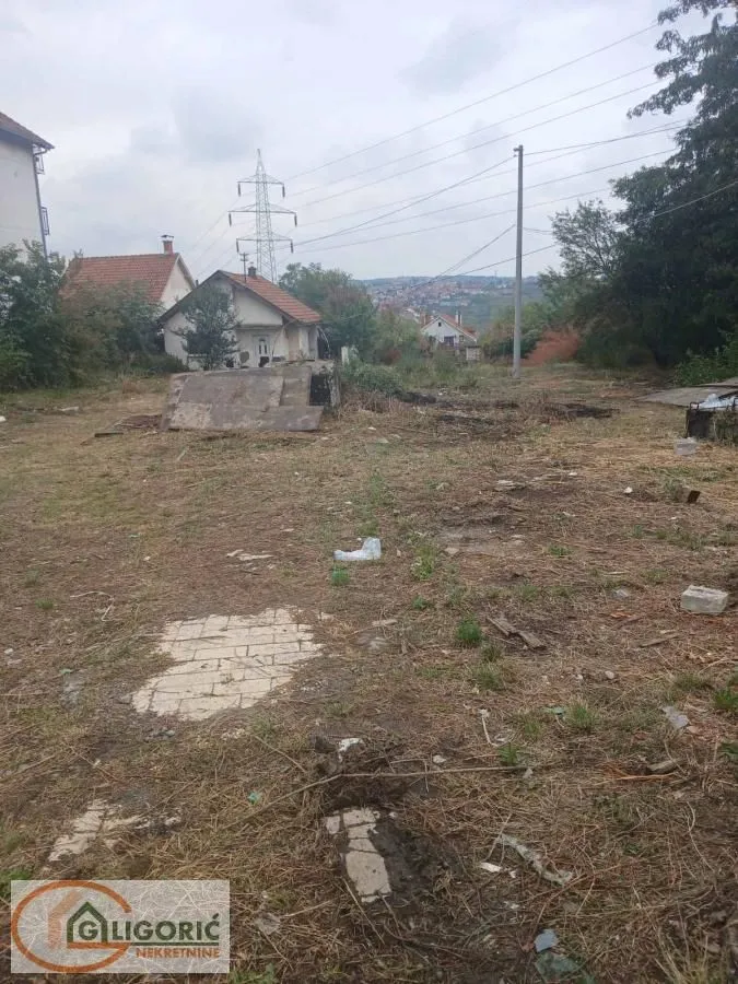 Pogled na plac sa travnatom površinom i okolnim kućama.