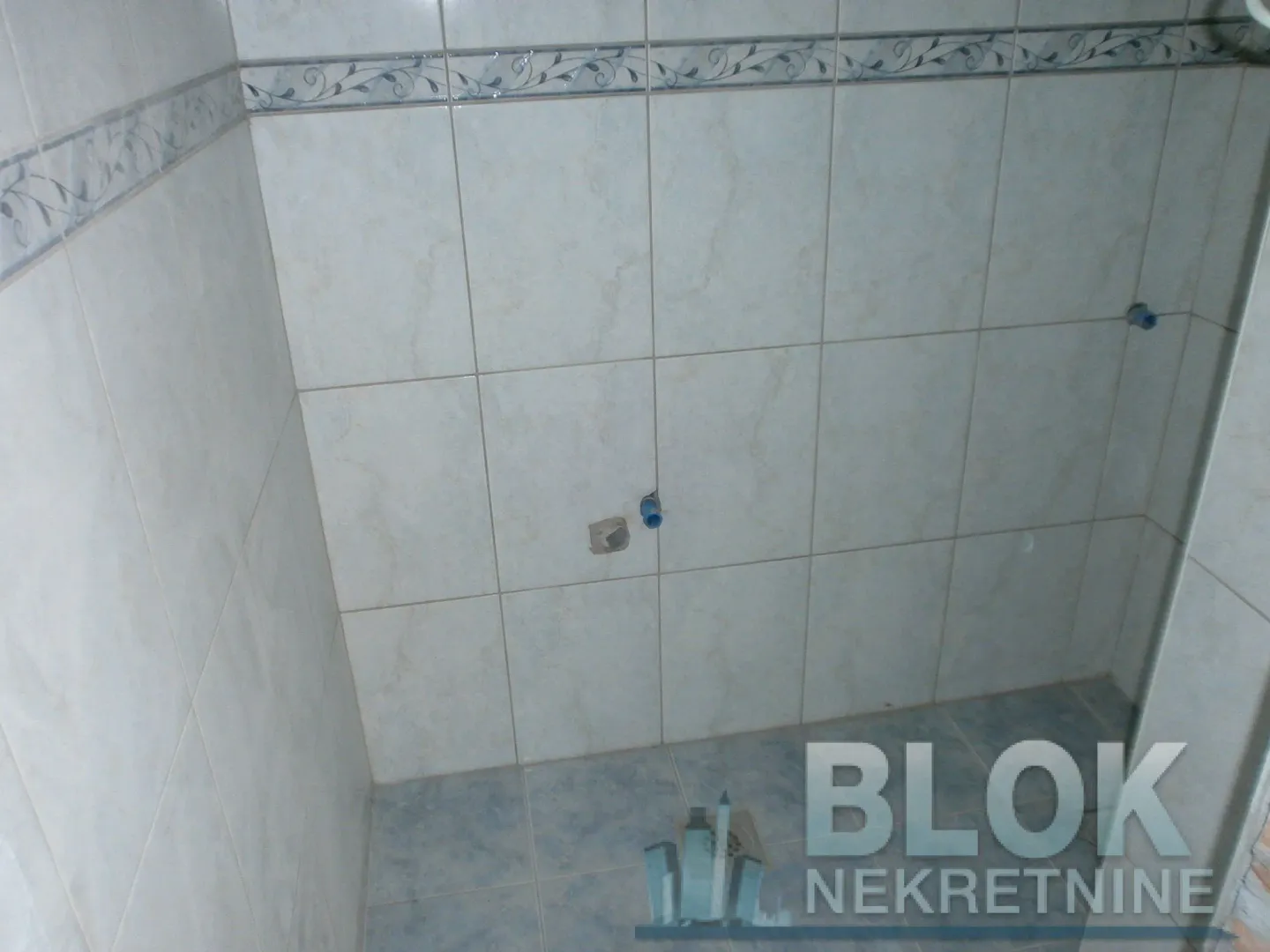 Bathroom lined with ceramic tiles and prepared plumbing connections for sanitary fixtures.