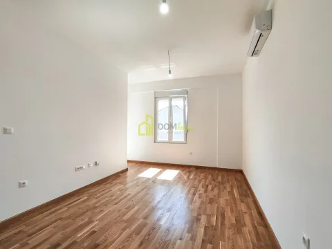 Prazna soba sa bijelim zidovima, drvenim podom i klima uređajem. - image 3