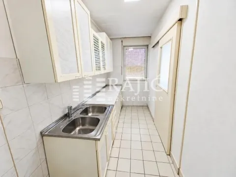 Small narrow kitchen with white cabinets and tiled floor. - image 4