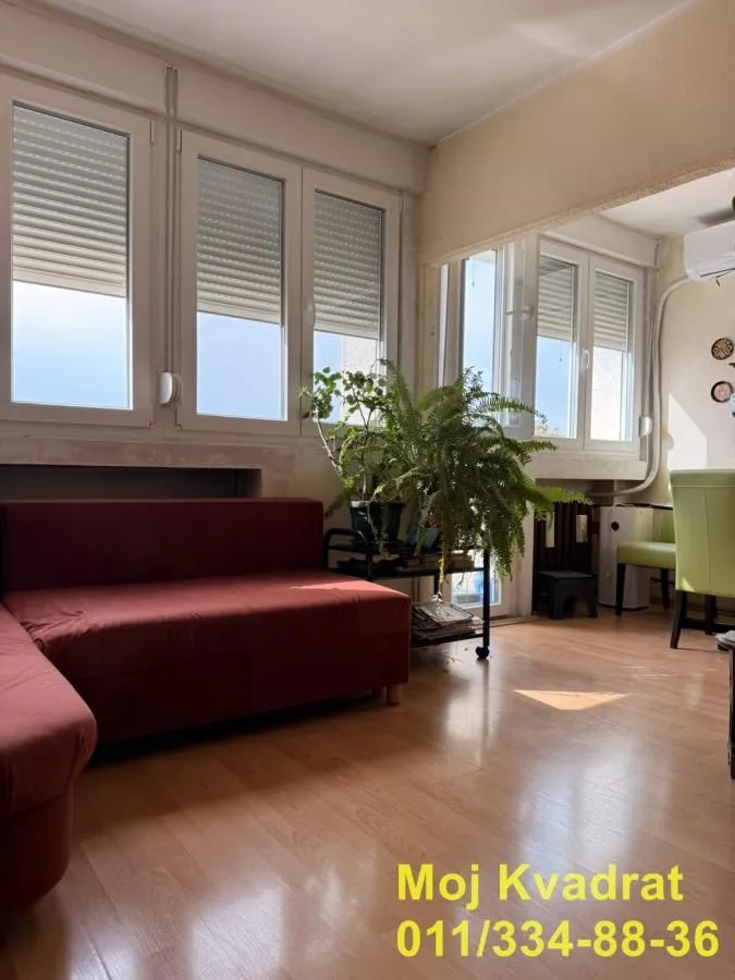 Dnevna soba sa garniturom i velikim prozorima koji propuštaju prirodnu svetlost.