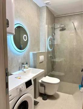 Modernly equipped bathroom with a walk-in shower, washbasin, and washing machine. - image 4