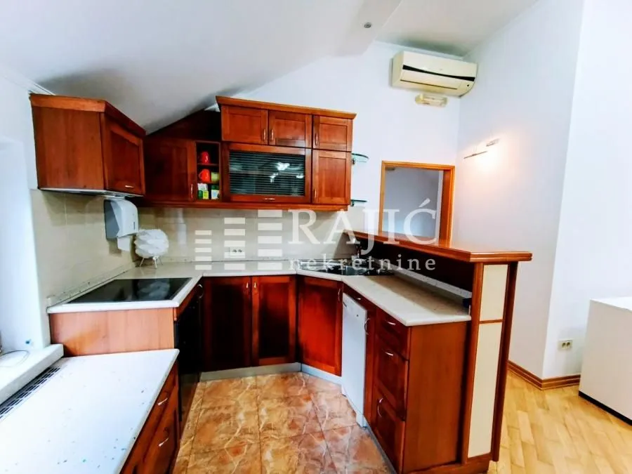Wooden kitchen with built-in appliances and a breakfast bar.