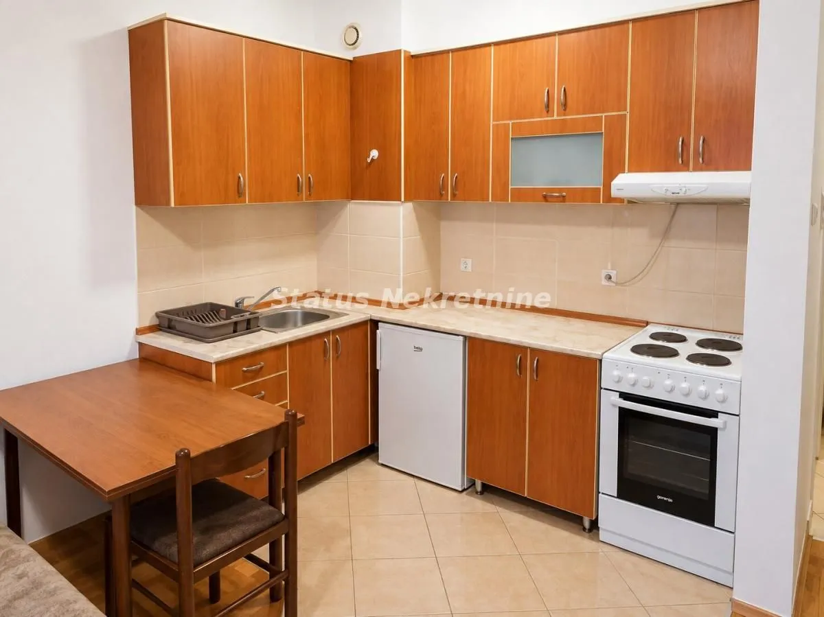 Small kitchen with wooden cabinetry, white appliances, and a dining table.