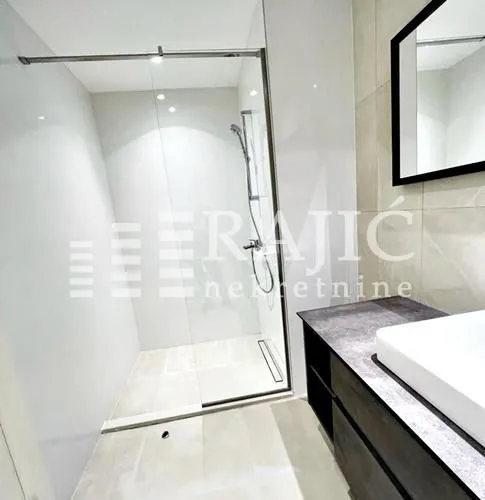 Modern bathroom with walk-in shower and washbasin.