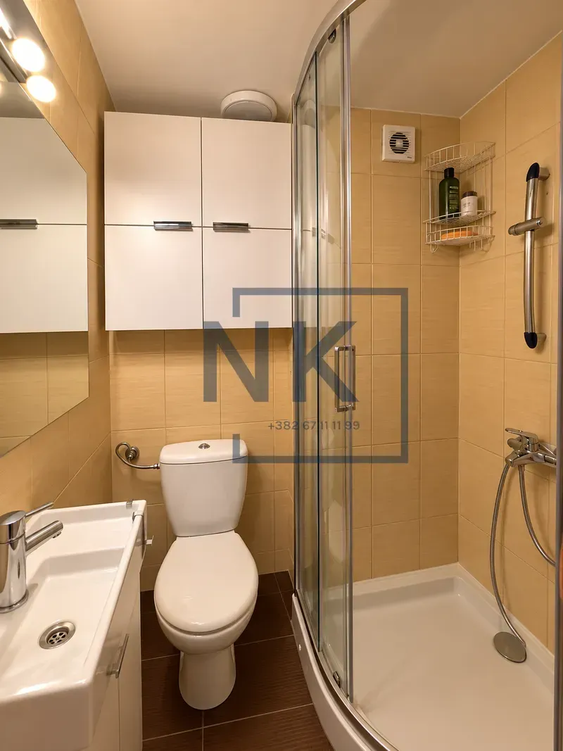 Compact bathroom with a shower cabin, washbasin, and toilet.