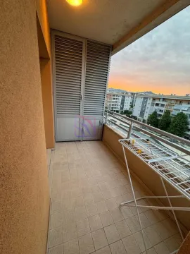 Covered balcony with a clothes drying rack and a city view. - image 6