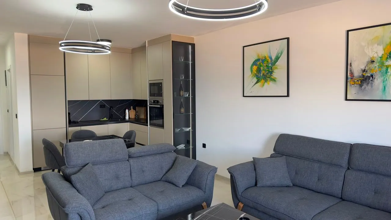 Moderan dnevni boravak sa garniturom i trpezarijom u pozadini.