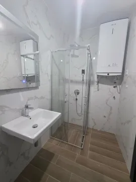 Savremeno opremljeno kupatilo sa tuš kabinom i bijelim mermernim pločicama. - image 12