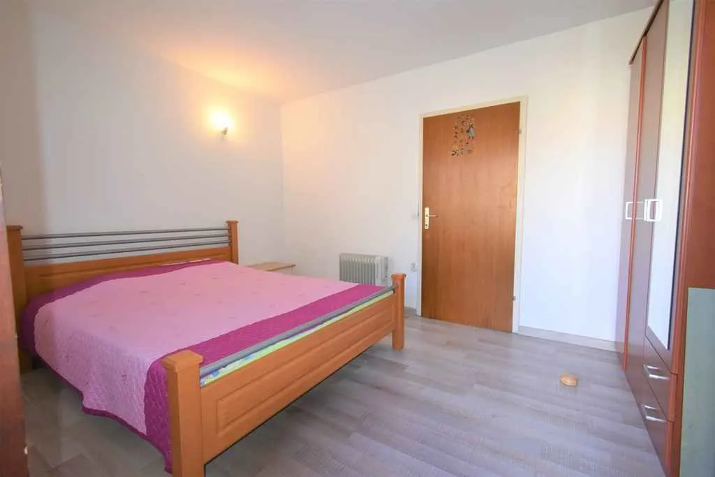 Bright bedroom featuring a large double bed and a wooden wardrobe.