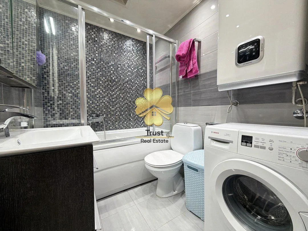 Modern bathroom equipped with a bathtub, shower enclosure, and washing machine.