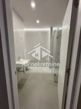 Pogled iz vrata na moderno opremljeno kupatilo sa umivaonikom i tuš kabinom. - image 12