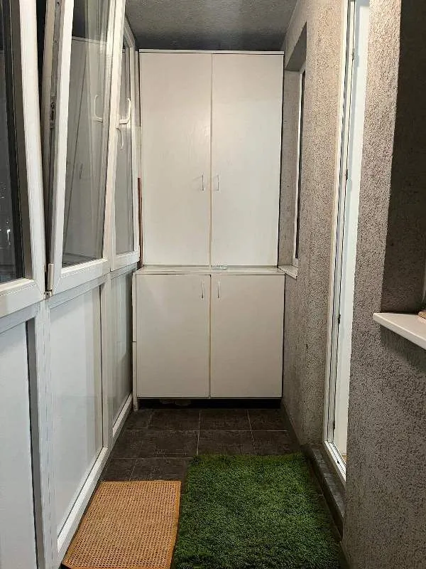 Zastakljeni balkon sa ugradnim ormarom i pločicama na podu.