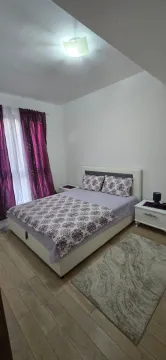 Furnished bedroom with a double bed and purple curtains. - image 6