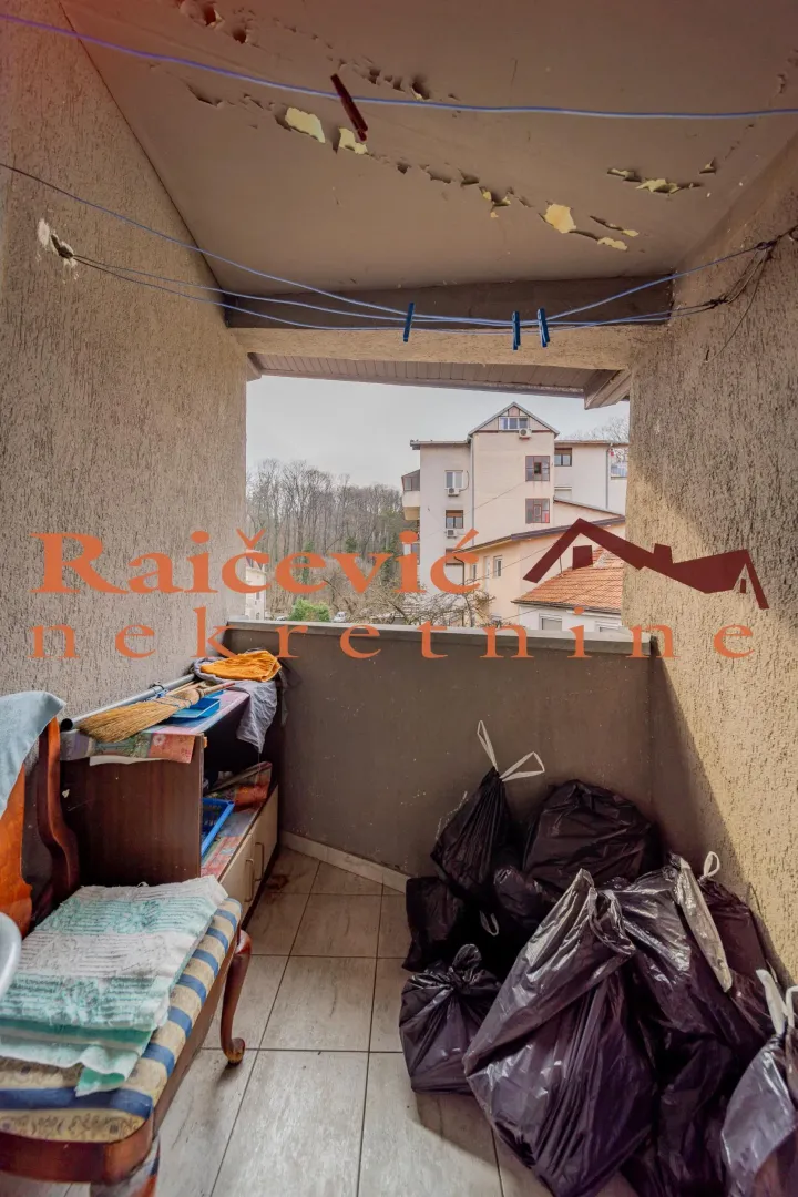 Manji natkriveni balkon sa policom i crnim vrećama za smeće.