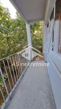 Covered balcony with a metal railing and a view of greenery. - image 10
