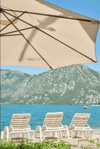 Pogled na more i planine sa ležaljkama i suncobranom.