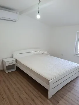Svetla spavaća soba sa belim krevetom, noćnim stočićem i klima uređajem. - image 4