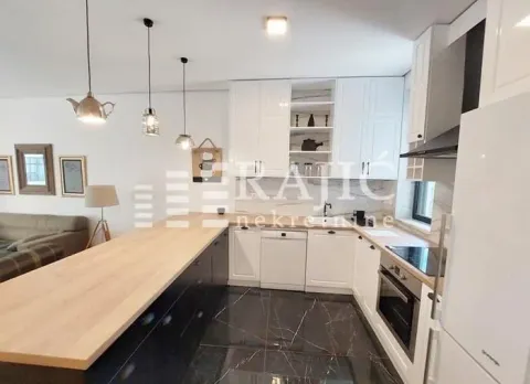 Modern kitchen with white cabinetry, a breakfast bar, and a dining area in the background. - image 3