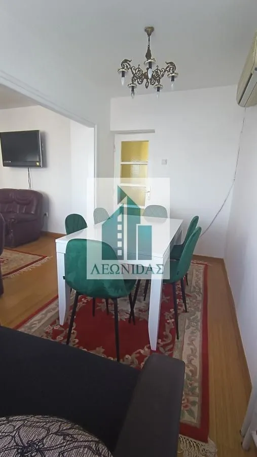 Dining area connected to the living room with a dining table and green chairs.