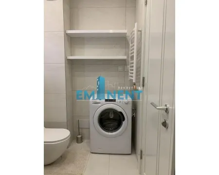 Bathroom with a washing machine, toilet bowl, and shelves above. - image 10